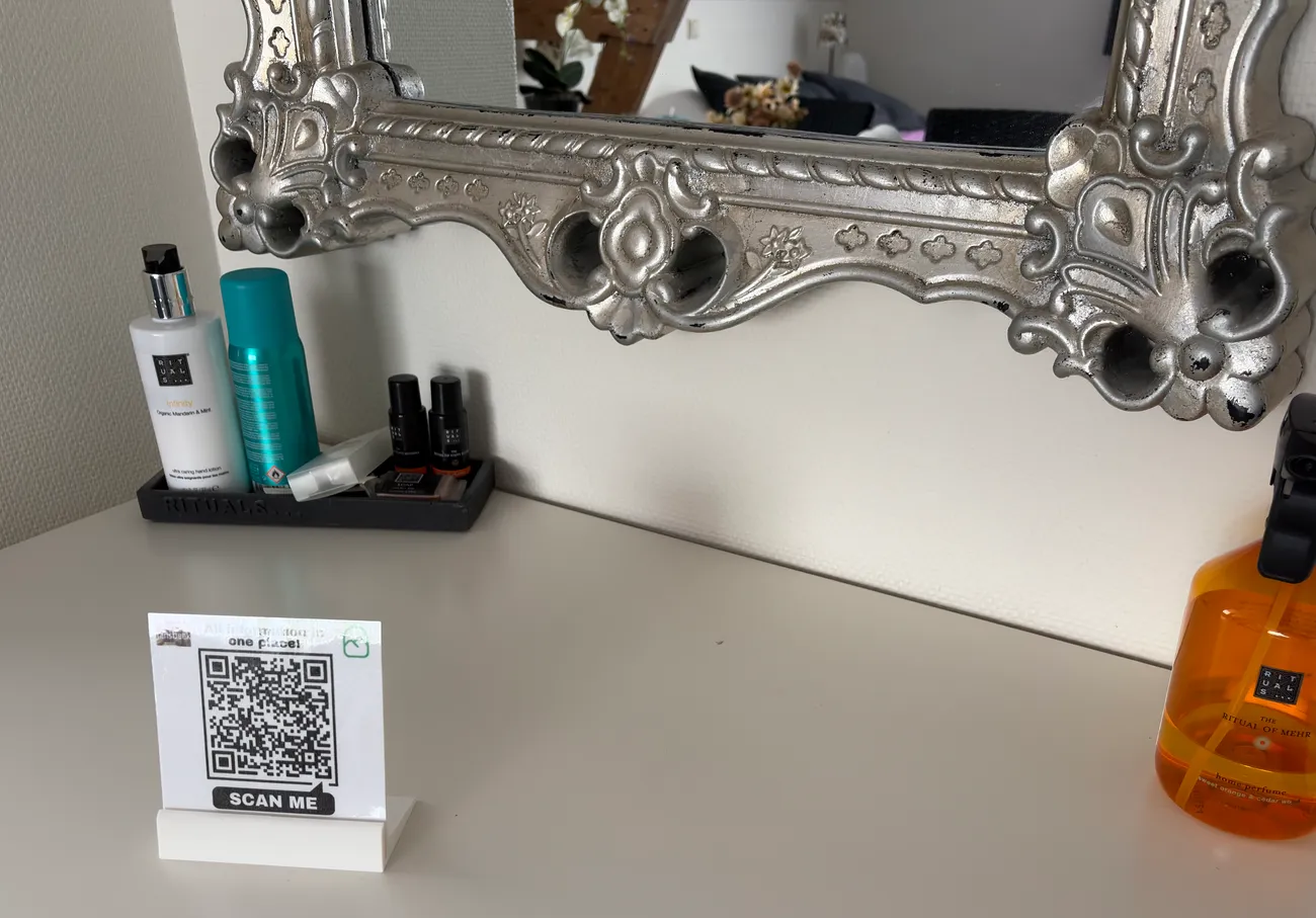 Een QR-kaartje op een witte kaptafel in een B&B-kamer, met een spiegel waarin de kamer te zien is