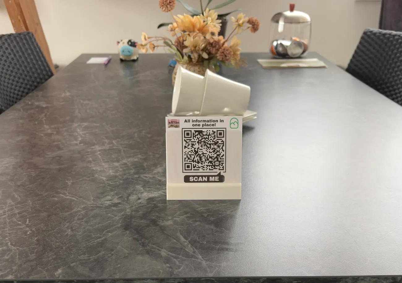 Een QR-kaartje op de tafel van een B&B-kamer, met bloemen en stoelen eromheen