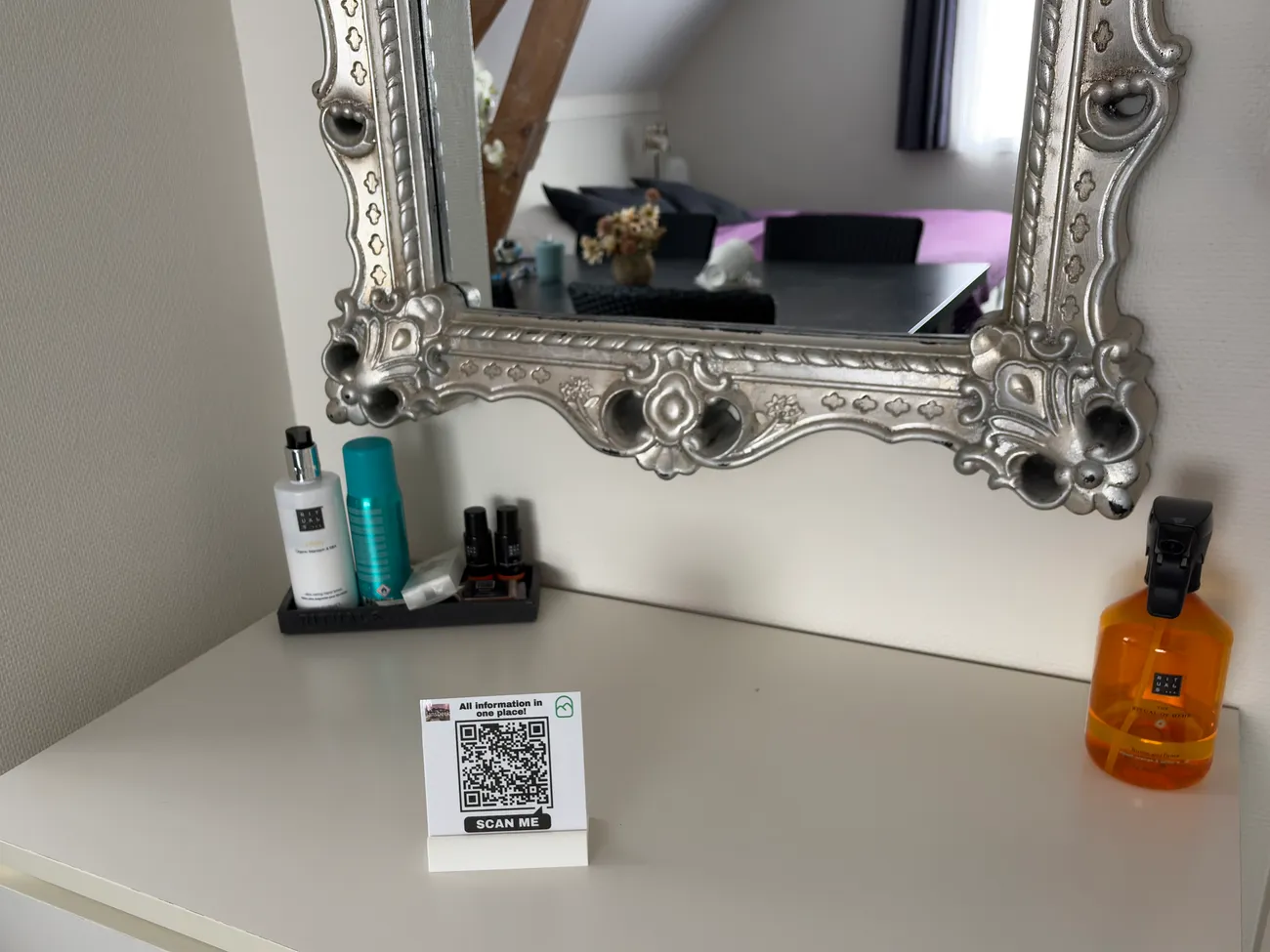 Een QR-kaartje op een kaptafel in een B&B-kamer, met daarboven een spiegel waarin de kamer te zien is