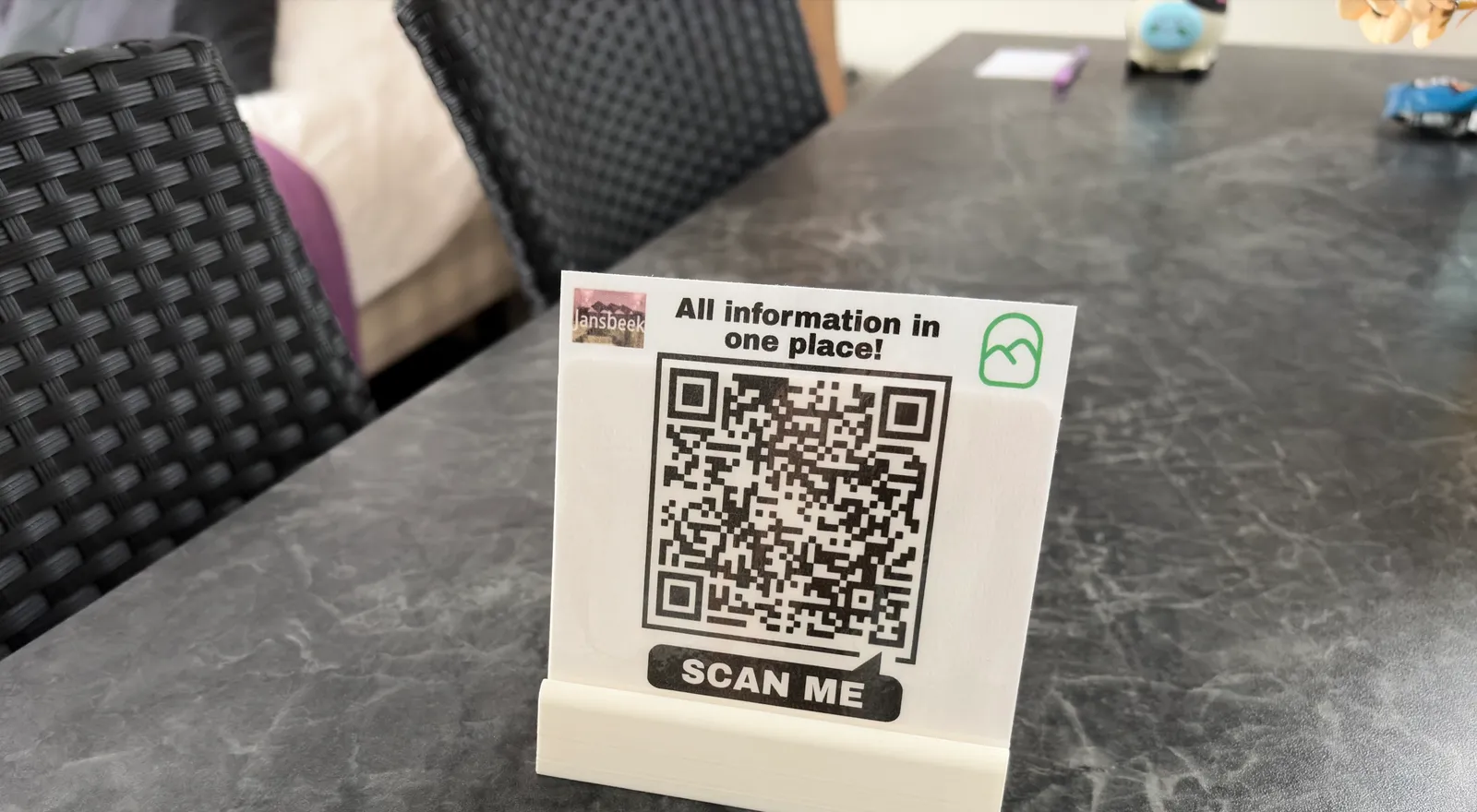 Een geprint QR-kaartje in een standaard op de tafel van een B&B-kamer, met het bed op de achtergrond
